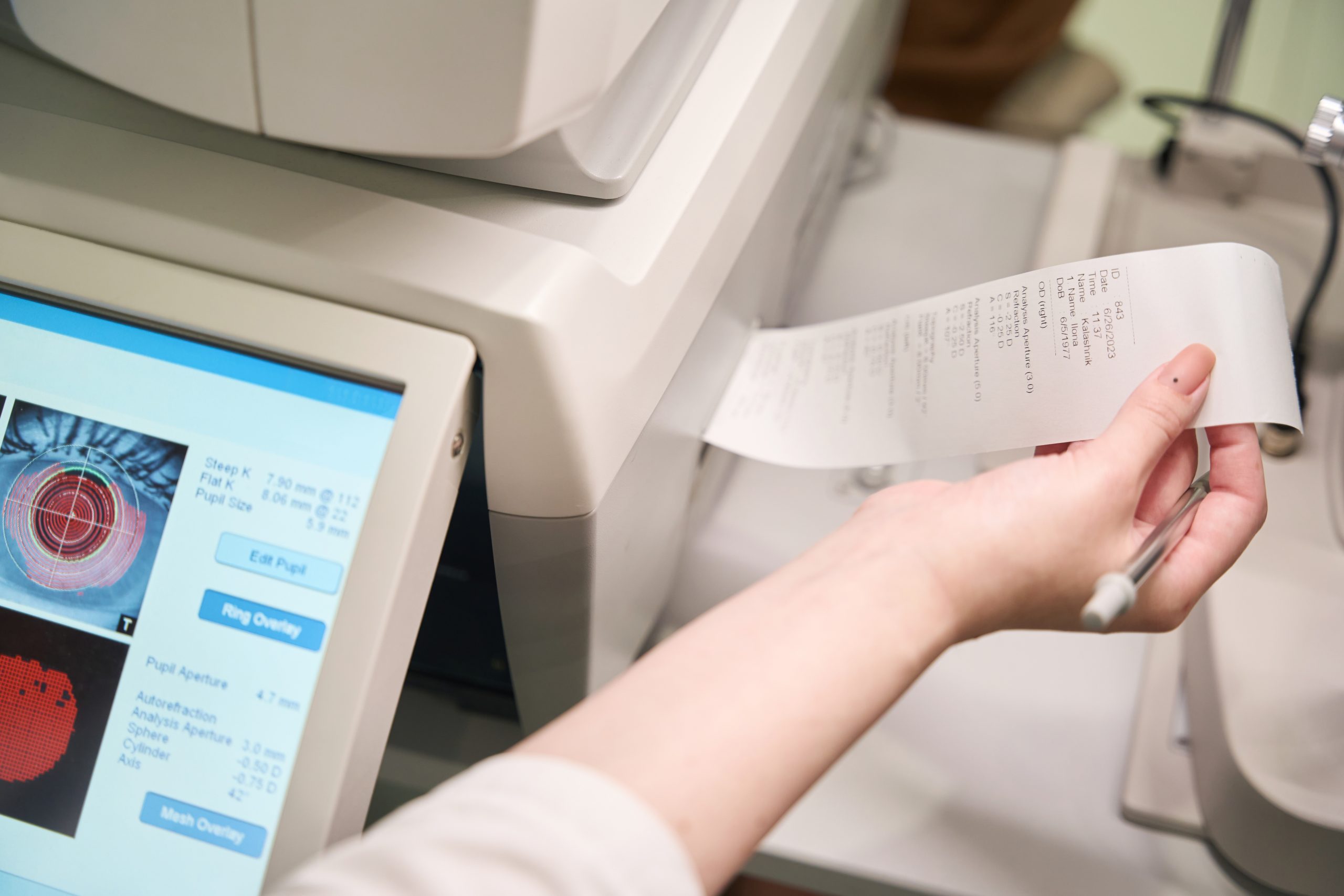Woman works on modern ophthalmological equipment, the device prints out the results