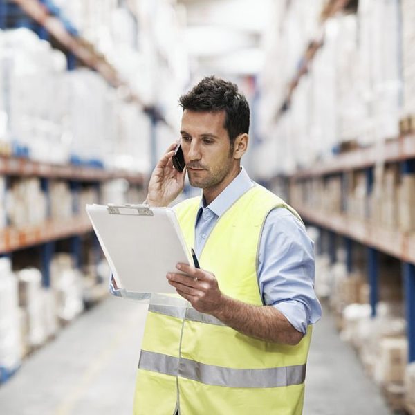 A young man in a warehouse taking orders on his mobile phone