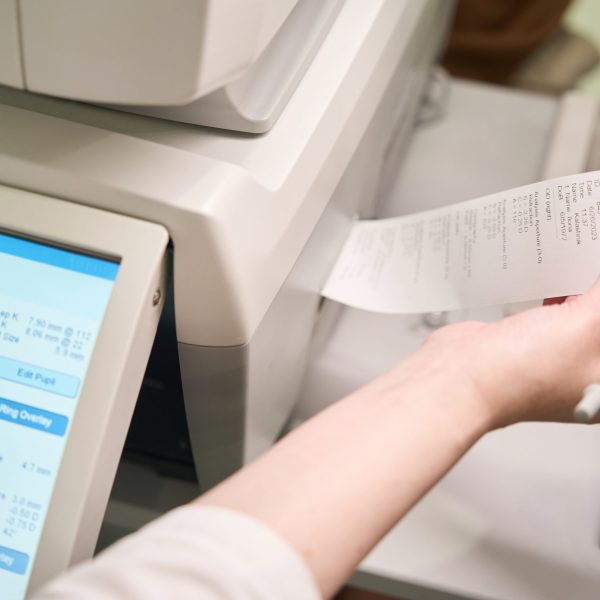 Woman works on modern ophthalmological equipment, the device prints out the results